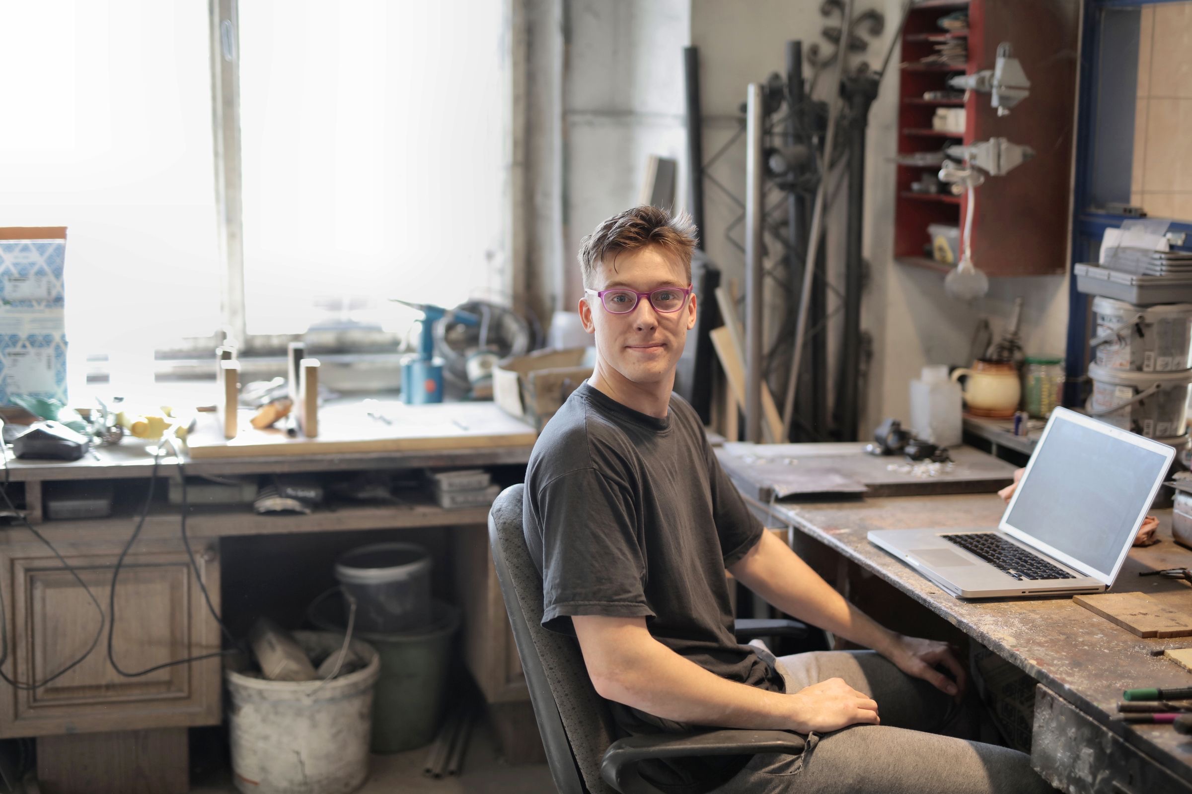 A founder working at a laptop in a small studio lit by a large window.