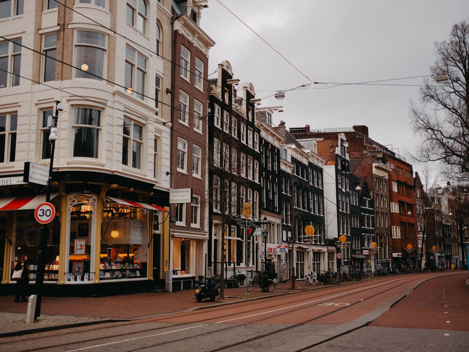 A street of small shops and workshops in Amsterdam with bicycles parked outside.