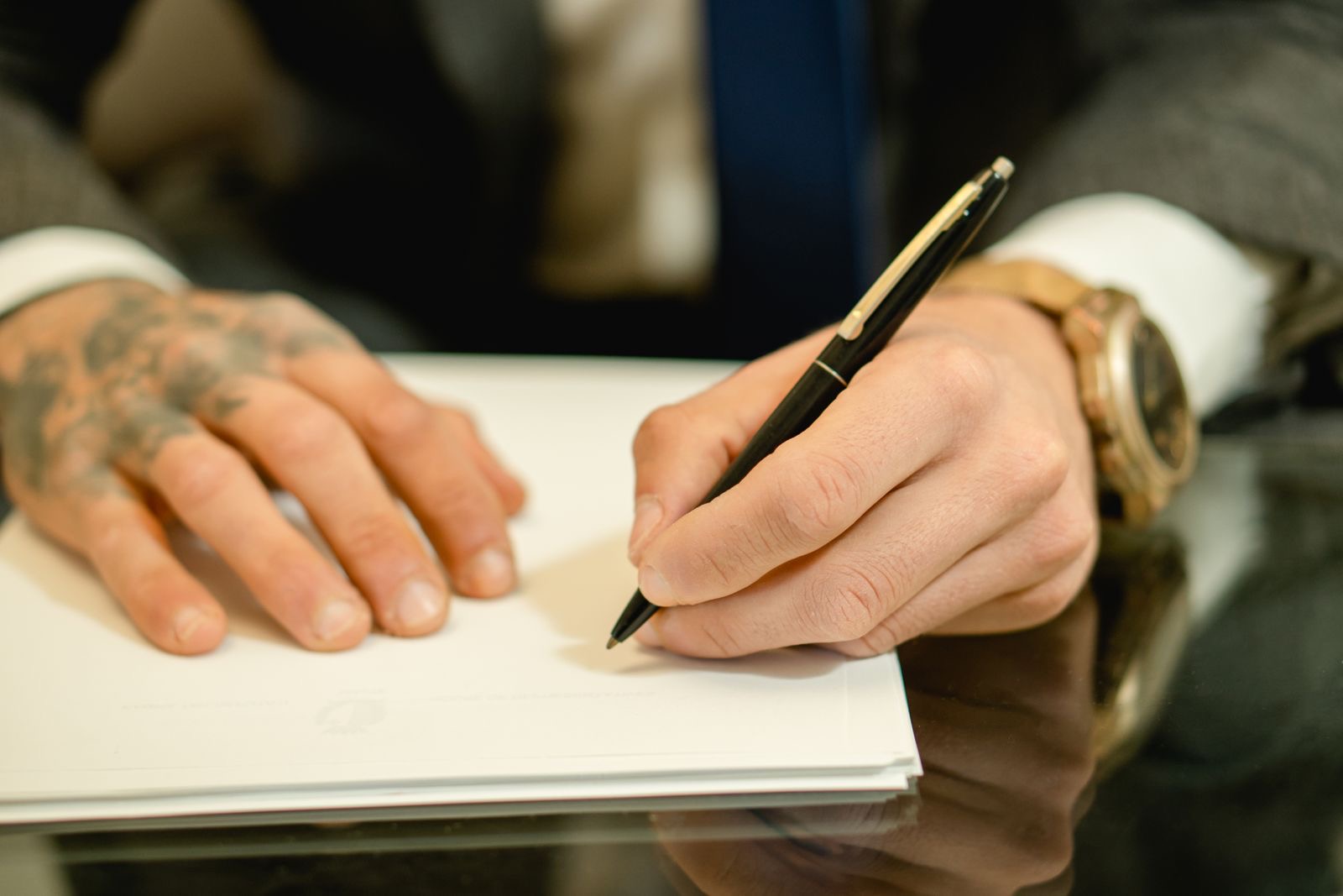 A pen signing a document beside a closed passport on a desk