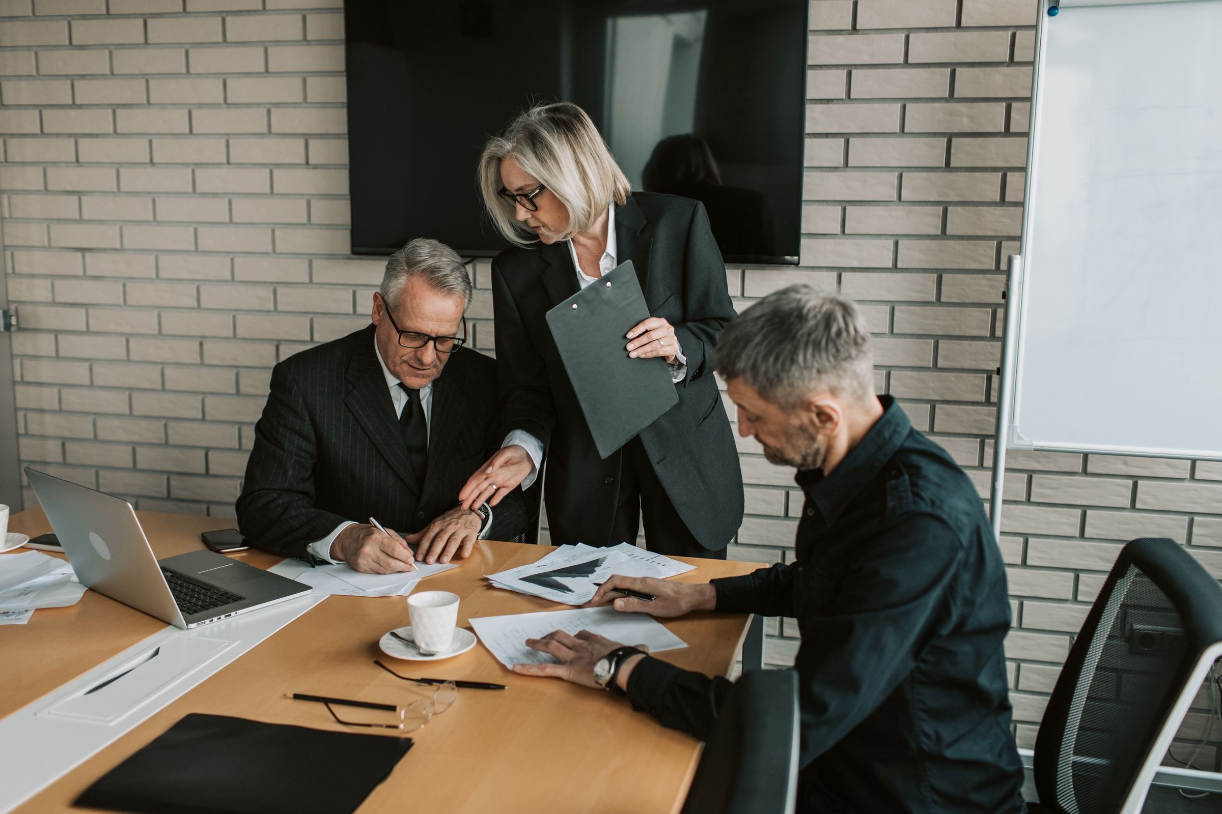 Executives of an international group reviewing documents at a boardroom table before setting up a Dutch subsidiary