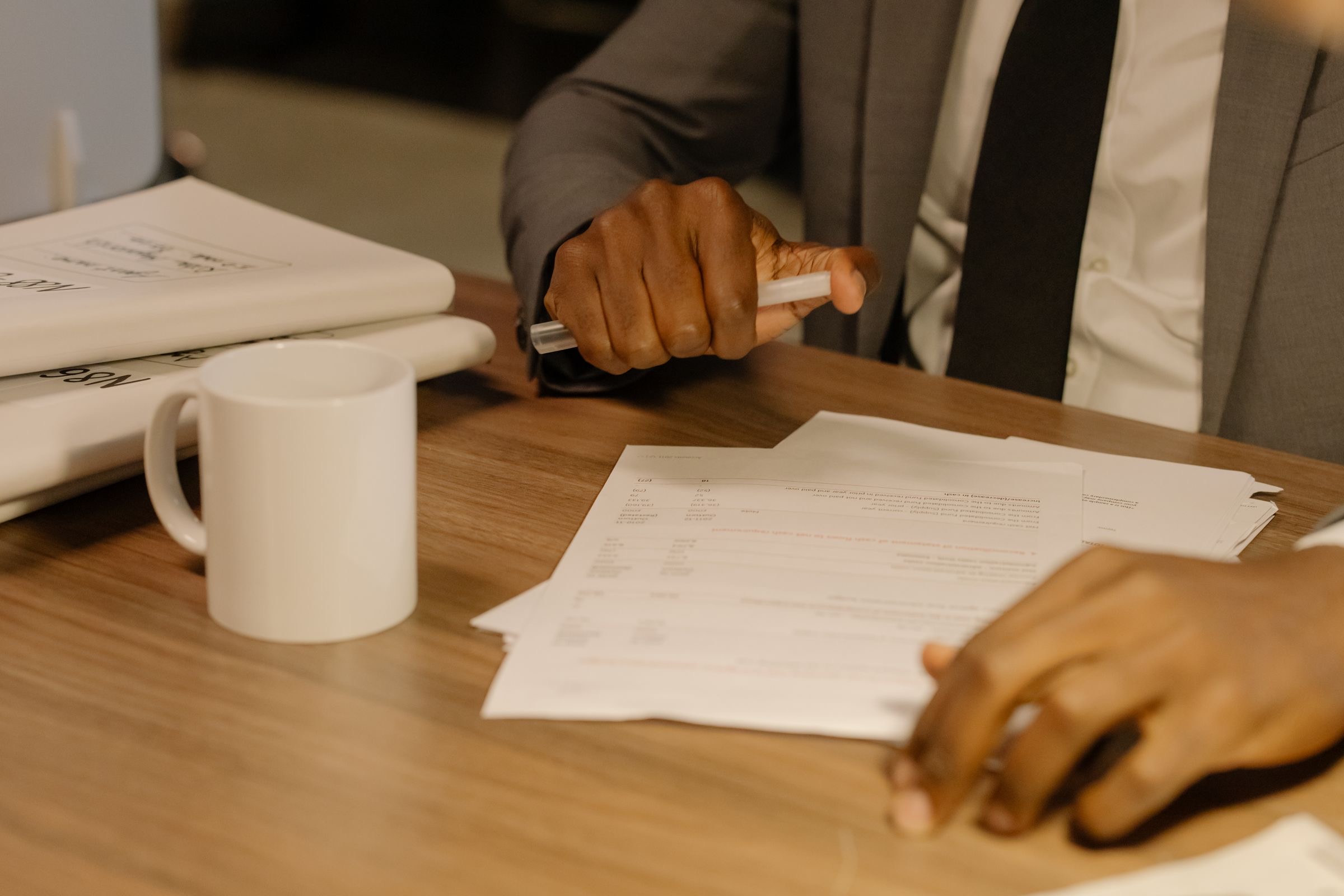 A notarial deed of share transfer and a shareholders' register open on a desk beside a pen