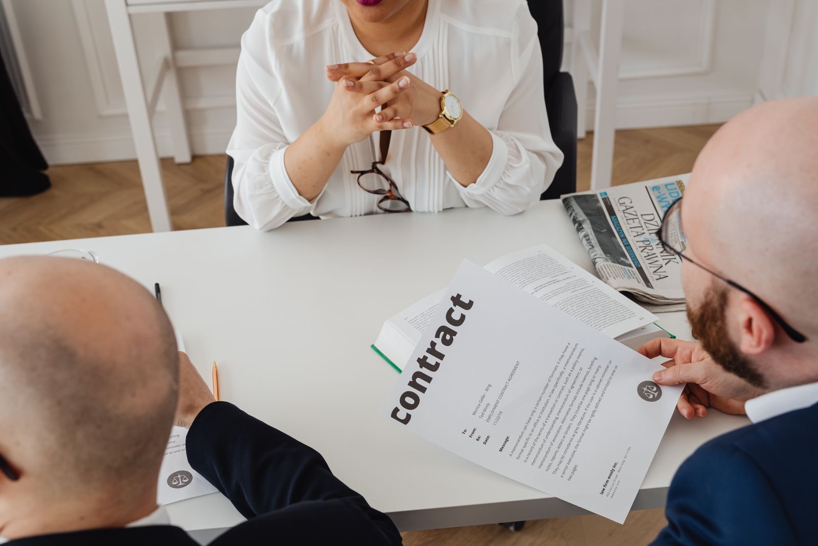 Two people at a table reviewing printed contract pages side by side.